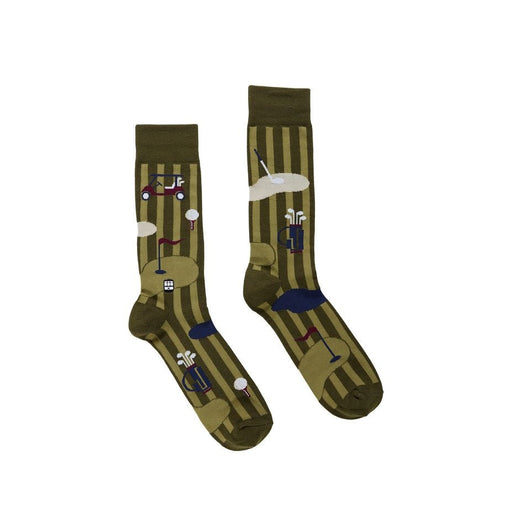 A pair of woven crew socks featuring a golf course pattern set against olive green stripes, including a miniature red-and-white golf cart, a blue bag of clubs, and a flagstick on a putting green