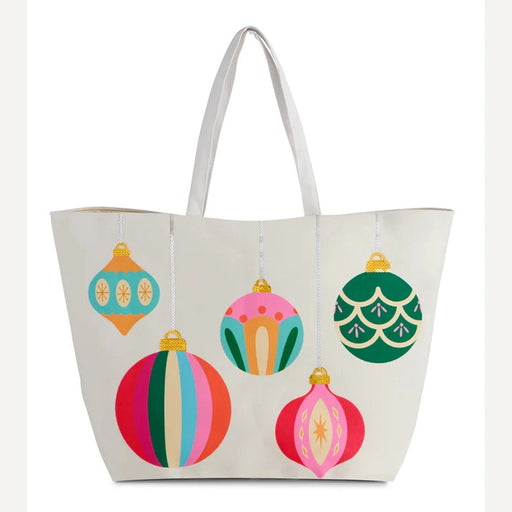 Canvas tote bag by Draper James featuring five vibrant holiday ornaments with gold sequined caps including a multi-colored striped bauble and a pink starburst teardrop ornament against a white background
