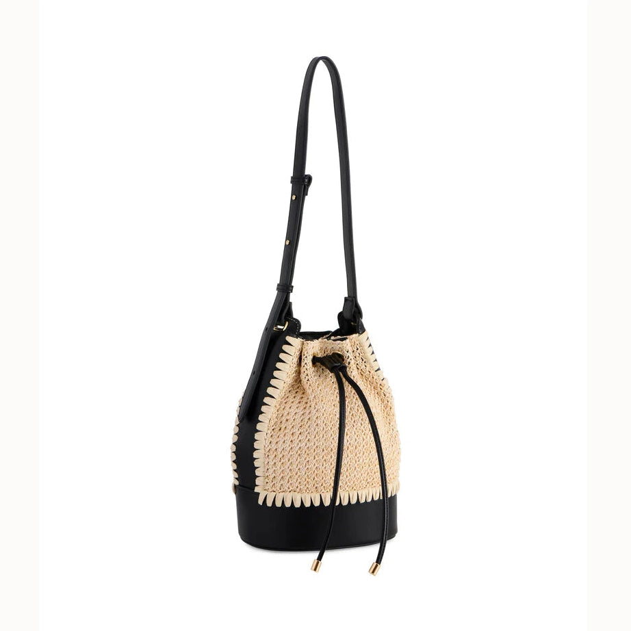 Studio photograph of a Chloé bucket bag featuring a woven beige raffia texture with iconic white scalloped trim, a sleek black leather base, and thin drawstring ties on a white background