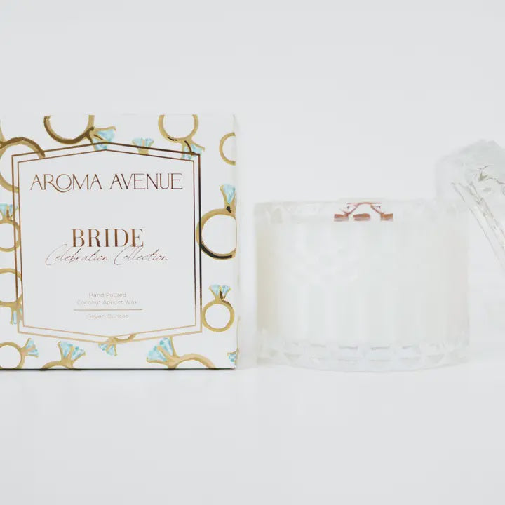 Commercial product photography by Aroma Avenue of a white Bride Celebration Collection candle box featuring gold ring illustrations with blue diamonds and a faceted clear glass container on a white background
