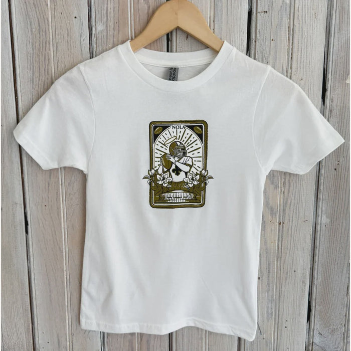 Graphic t-shirt design of a New Orleans football player depicted as a saint with a halo and fleur-de-lis jersey, featuring the Superdome landmark framed by magnolia blossoms and NOLA text in an Art Nouveau style