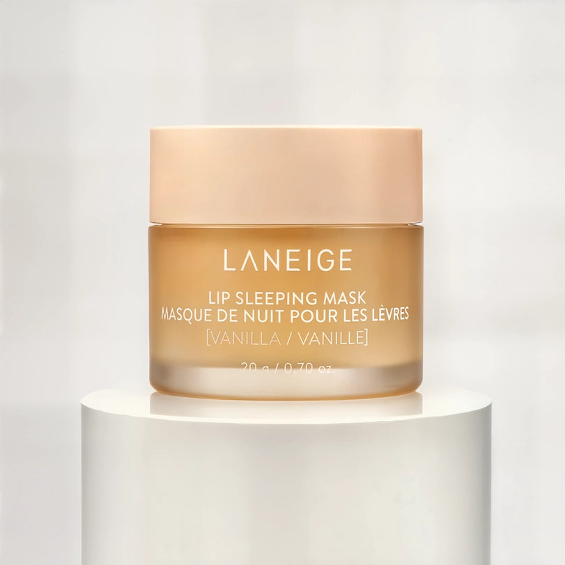 Studio product photograph by Laneige featuring a vanilla lip sleeping mask jar on a white pedestal with a translucent amber base and a soft peach-colored lid displaying clean white typography