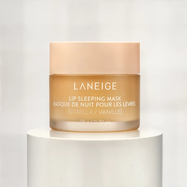 Studio product photograph by Laneige featuring a vanilla lip sleeping mask jar on a white pedestal with a translucent amber base and a soft peach-colored lid displaying clean white typography