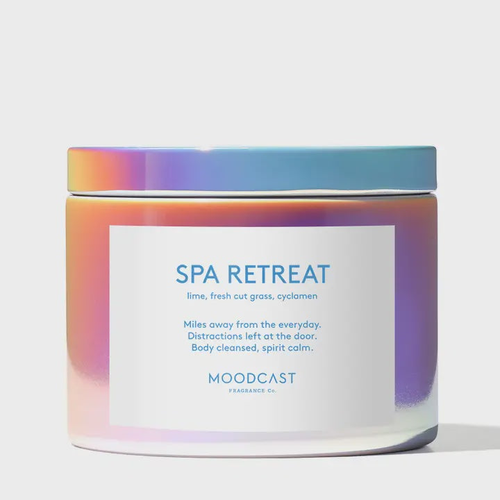 Product photograph of a Moodcast Fragrance Co. Spa Retreat scented candle featuring a white rectangular label with blue text against a shimmering iridescent holographic glass jar and lid on a clean white background