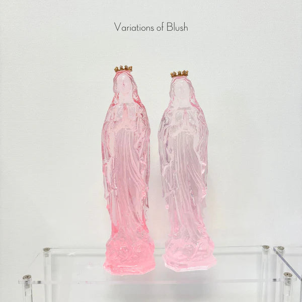 Translucent pink resin sculptures from the Variations of Blush series showcasing two iconic Madonna figures adorned with small gold crowns and posed in prayer atop a transparent acrylic display stand