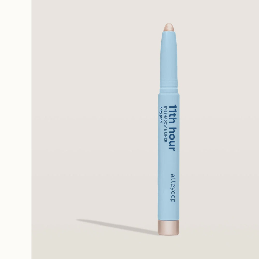Studio product photography by Alleyoop of the 11th Hour Eyeshadow and Liner in Baby Pearl on a neutral background featuring a light blue barrel with a shimmering cream tip and metallic base