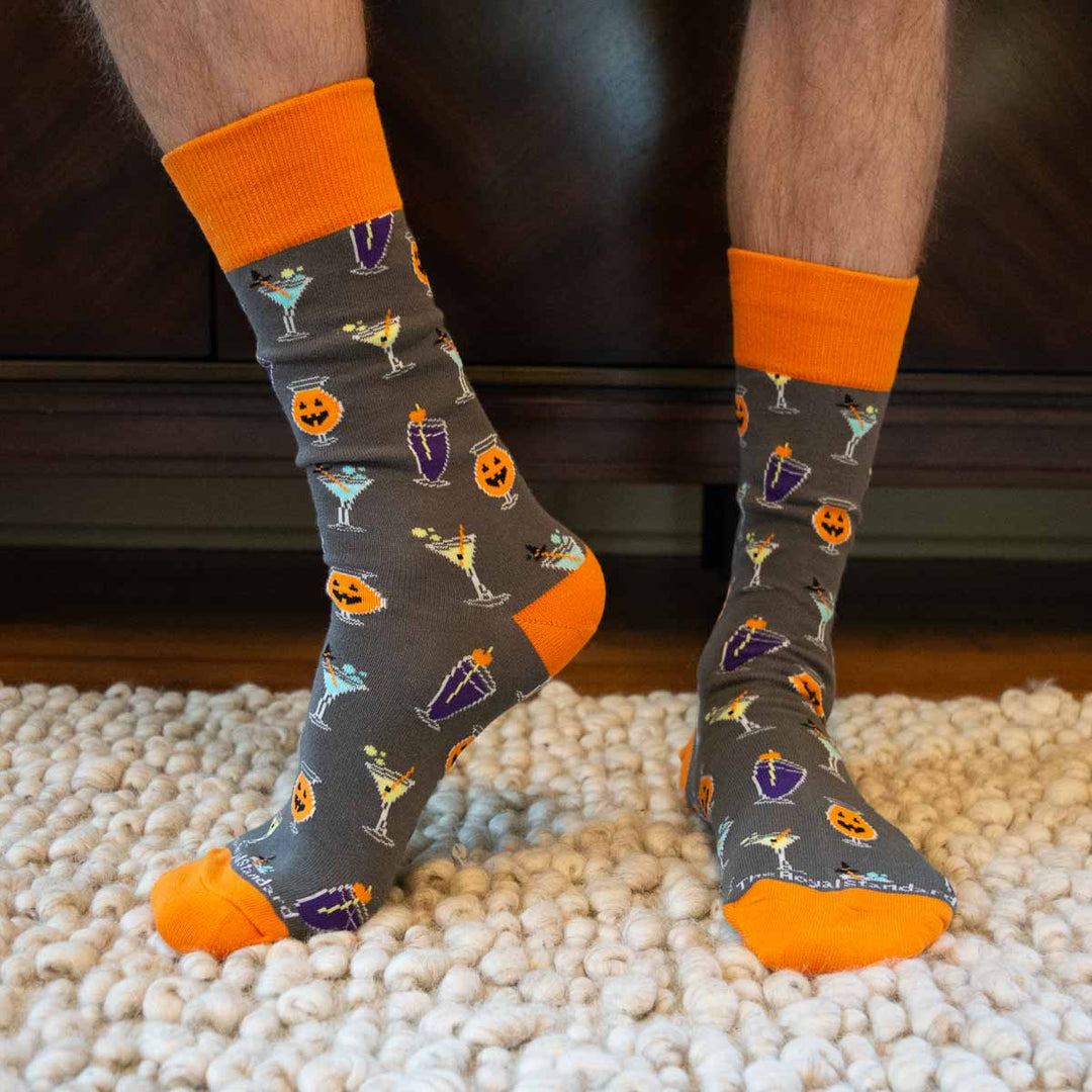 Digital photograph of The Royal Standard socks worn by a person on a white shag rug featuring a grey background with bright orange accents and a pattern of jack-o&