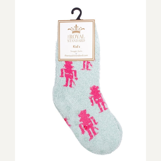 Product photography by The Royal Standard featuring a mint green fuzzy kid's snuggle sock with hot pink robot designs, a branded paper tag, and clear non-slip grippers on the sole
