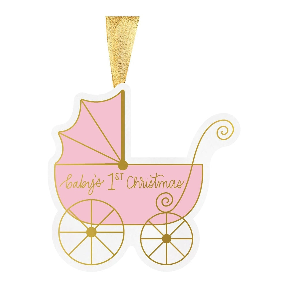 Graphic illustration of a pink baby carriage Christmas ornament on a white background featuring gold metallic script reading baby's 1st Christmas, vintage spoked wheels, and a shimmering gold ribbon