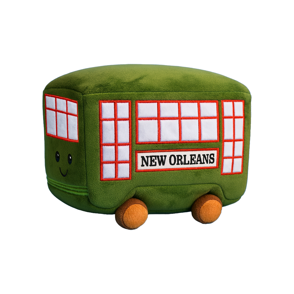 Plush toy souvenir of a green New Orleans streetcar representing the historic St. Charles Avenue line featuring a friendly embroidered smiley face, red-bordered windows, and soft brown wheels