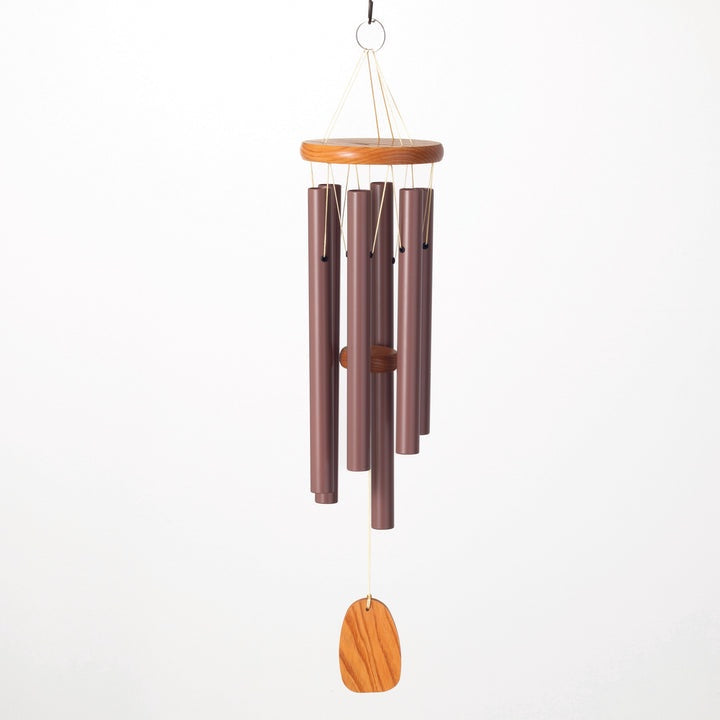 Aluminum and cherry wood wind chime by Woodstock Percussion hanging against a white studio background, featuring six plum-colored metallic tubes, a circular clapper, and a teardrop-shaped wind catcher with a natural wood grain
