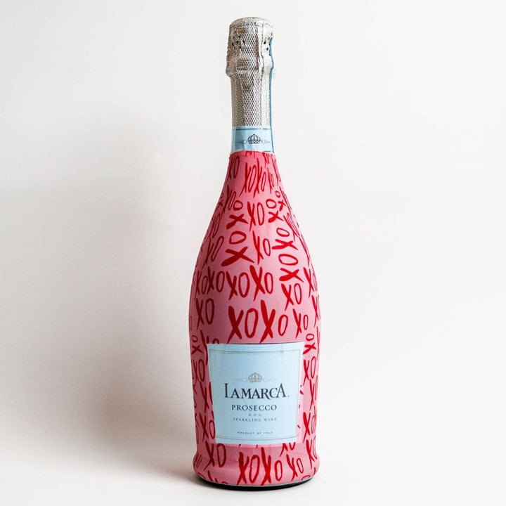 La Marca Prosecco bottle wearing a pink wrap printed with red XOXO
