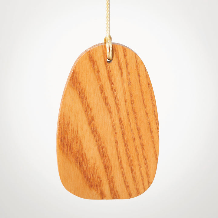 Photograph of a smooth egg-shaped wooden tag suspended in a neutral studio environment featuring vertical oak-colored grain patterns and a cream cord threaded through a hole at the top