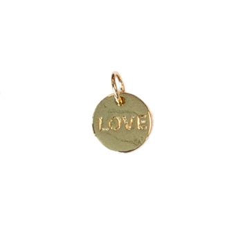 Gold-toned metal jewelry charm featuring a circular pendant with the word LOVE embossed in block letters and a small jump ring attached to its top against a stark white background