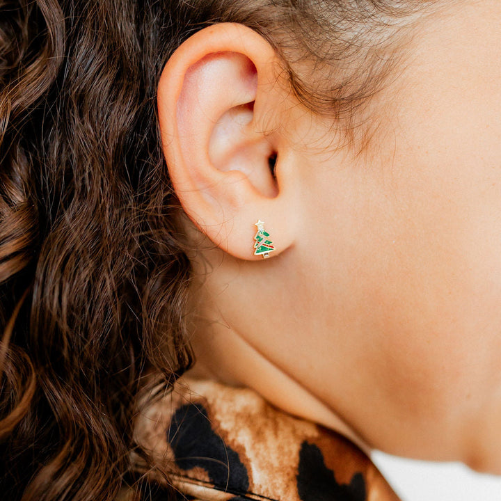 Photograph of a vibrant green enamel Christmas tree earring worn on a person&
