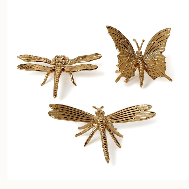Gold-finished metal sculptures of one butterfly and two dragonflies set against a plain white background featuring intricate linear wing textures, segmented abdomens, and slender legs
