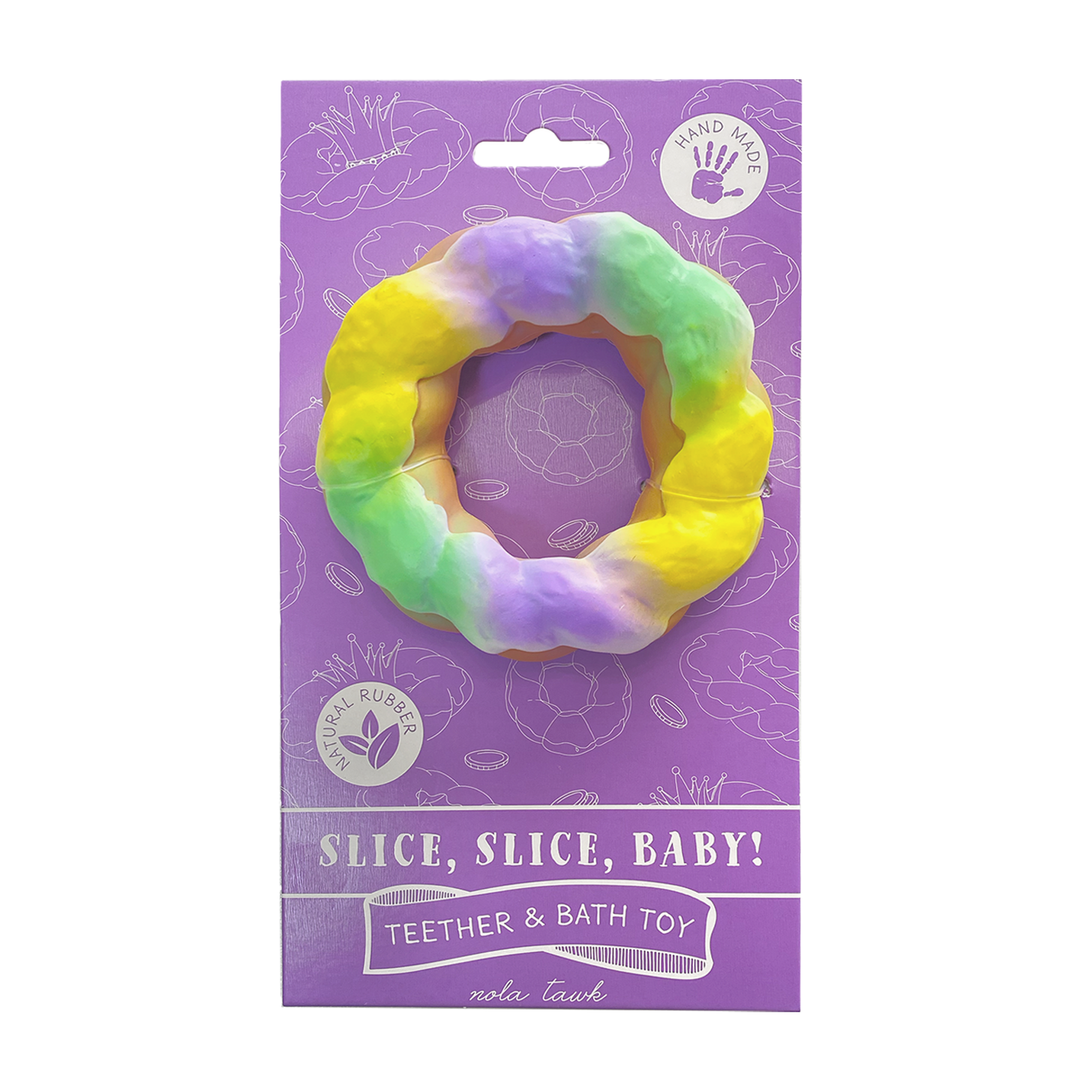 Natural rubber teether by nola tawk featuring a New Orleans King Cake bath toy with pastel yellow, green, and purple icing on a purple retail card with a bumpy texture and the slogan Slice, Slice, Baby