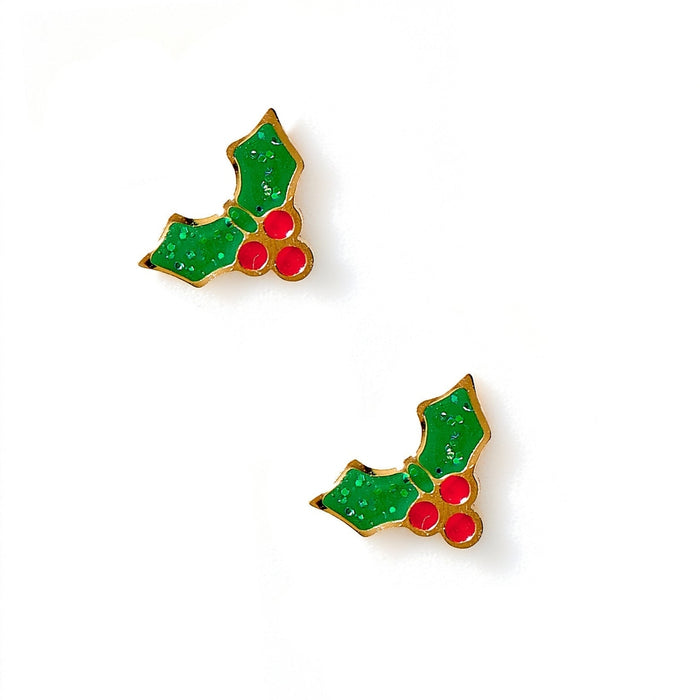 Enamel and gold-tone metal stud earrings featuring green glitter-infused holly leaves and three bright red berries on a minimalist white background