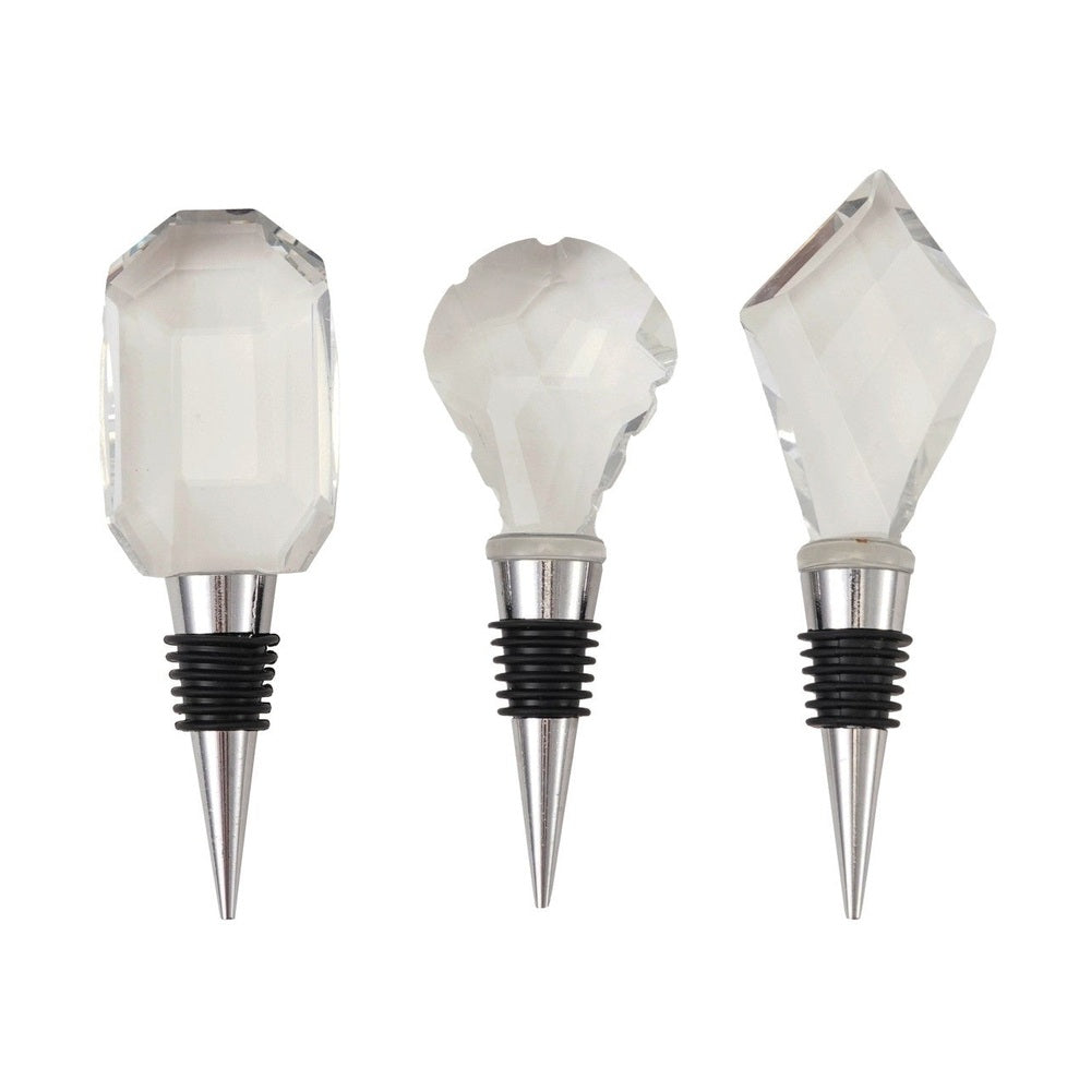 Polished crystal and chrome metal wine stoppers set against a plain white background featuring faceted glass toppers in rectangular, rounded, and diamond shapes with black rubber airtight seals on tapered silver stems