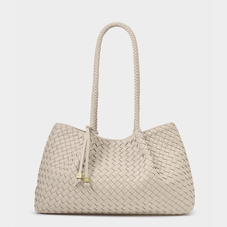 Woven leather tote bag by Bottega Veneta against a neutral backdrop featuring the signature intrecciato weave, a long braided shoulder handle, and a decorative leather tie with gold-toned cube charms