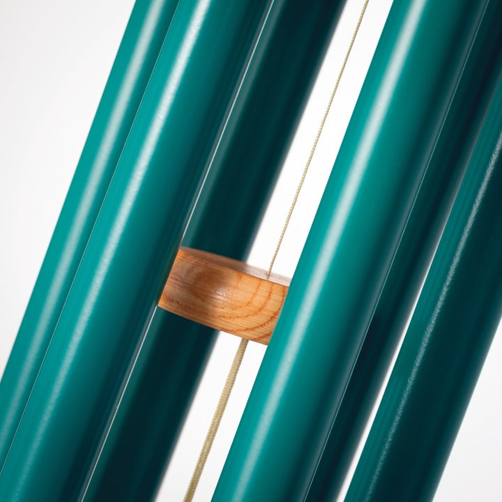Product photograph of emerald teal metal wind chimes featuring a circular natural wood striker and a thin beige suspension cord against a white background