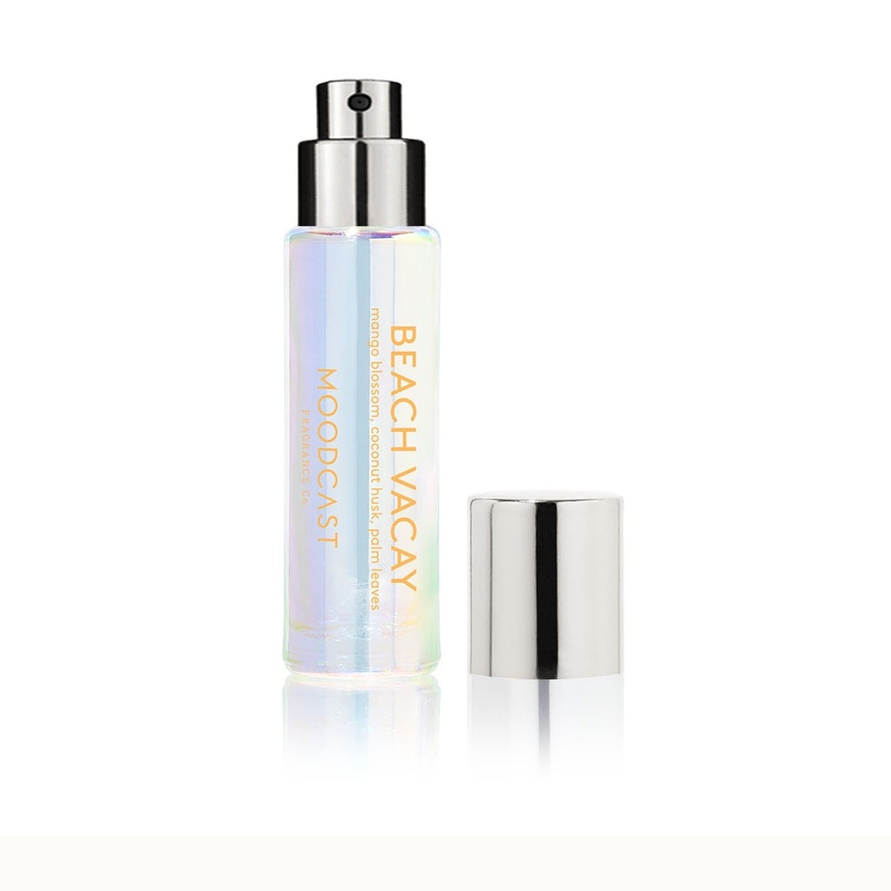 Studio product photograph of Moodcast Fragrance Co. Beach Vacay perfume featuring an iridescent holographic glass bottle, a silver metallic pump with a detached lid, and yellow text notes of mango blossom and coconut husk