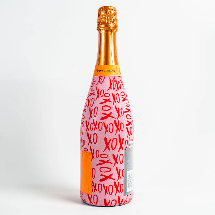 Side view of a champagne bottle in a pink and red XOXO print wrap