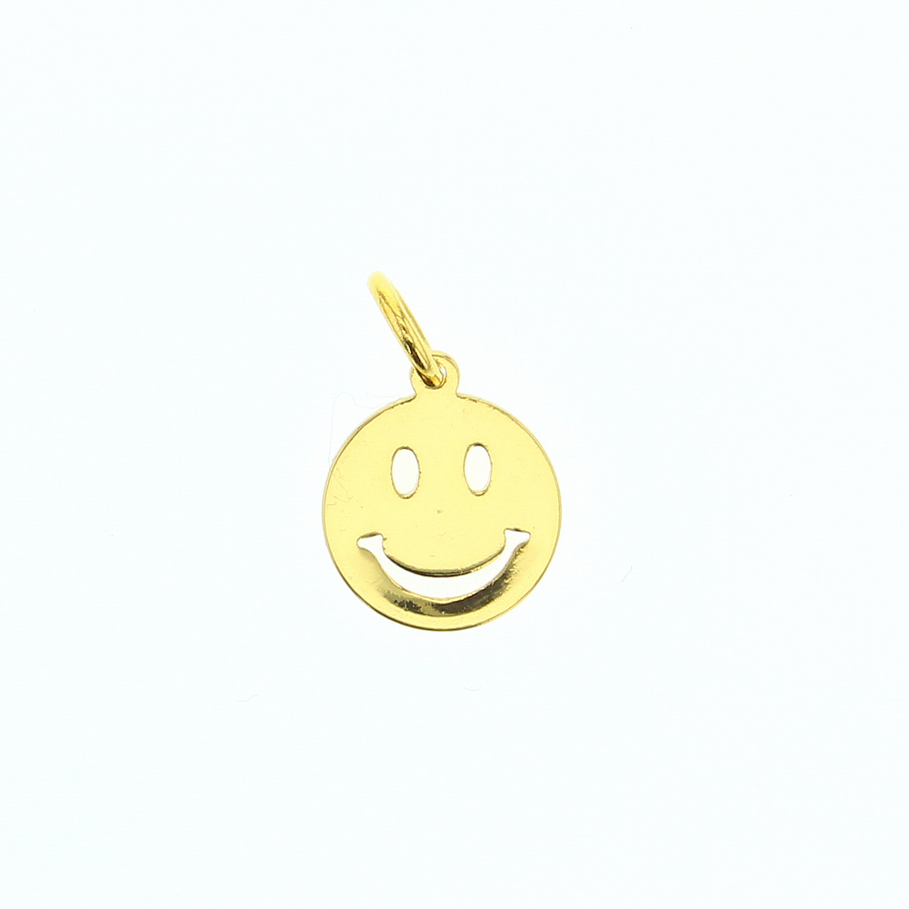 Gold jewelry charm of an iconic smiley face centered on a white background featuring cutout oval eyes, a wide curved smile, and a polished yellow-gold reflective finish with a small top bail