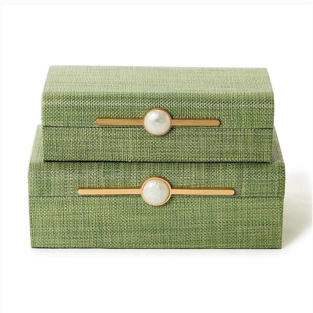 Grasscloth and gold-finished metal decorative boxes stacked on a white background showcasing a sage green basketweave texture, elongated horizontal gold-tone hardware, and iridescent white marble-like central accents