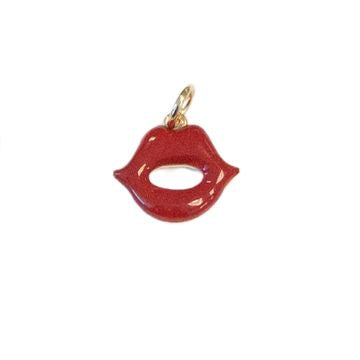 Enamel and gold-toned metal charm of slightly parted red lips on a white background featuring a shimmering glitter finish and a small polished gold hanging loop