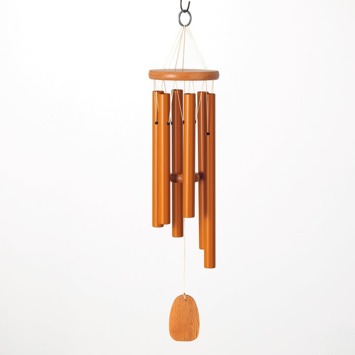 Wood and metal wind chime featuring six amber-hued tubes of graduated lengths, a circular wooden suspension plate, and a teardrop-shaped wooden sail suspended against a minimalist white background