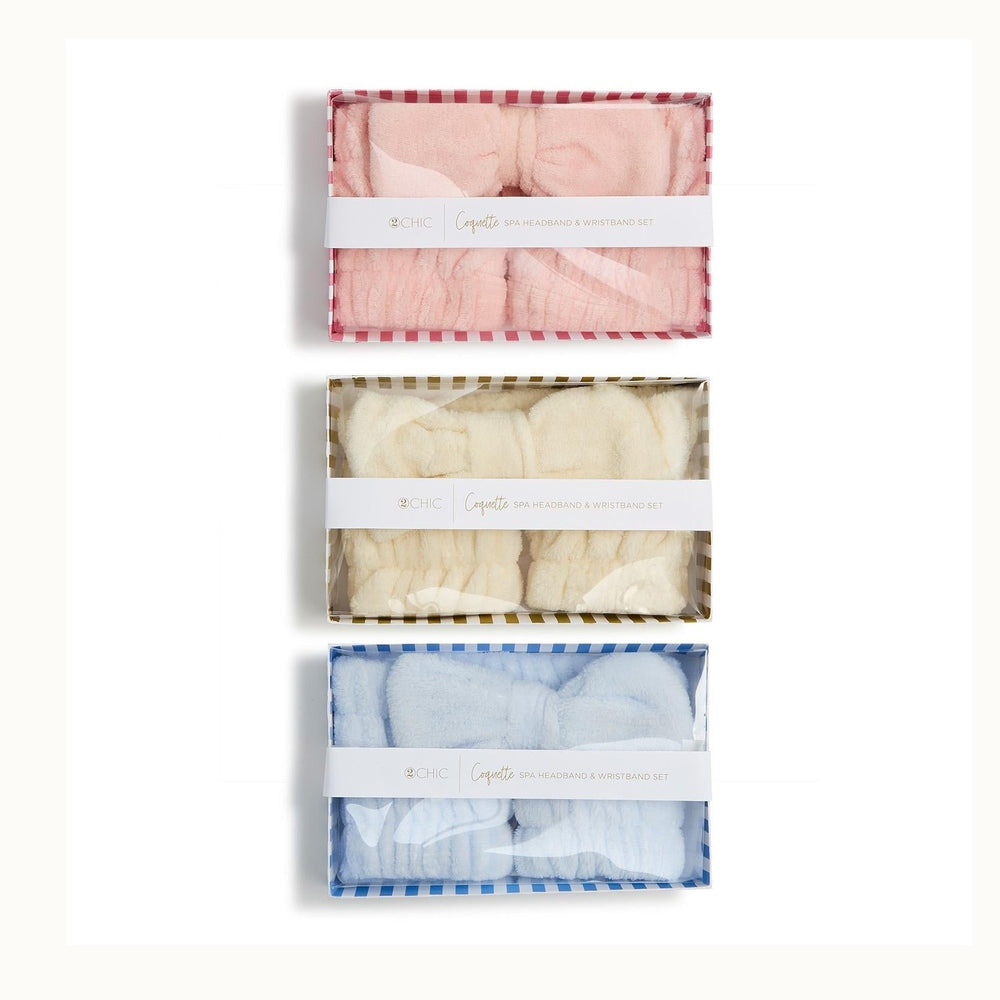 Product photograph by 2CHIC of three Coquette spa headband and wristband sets in pastel pink, cream, and light blue plush textures presented in striped boxes on a white background