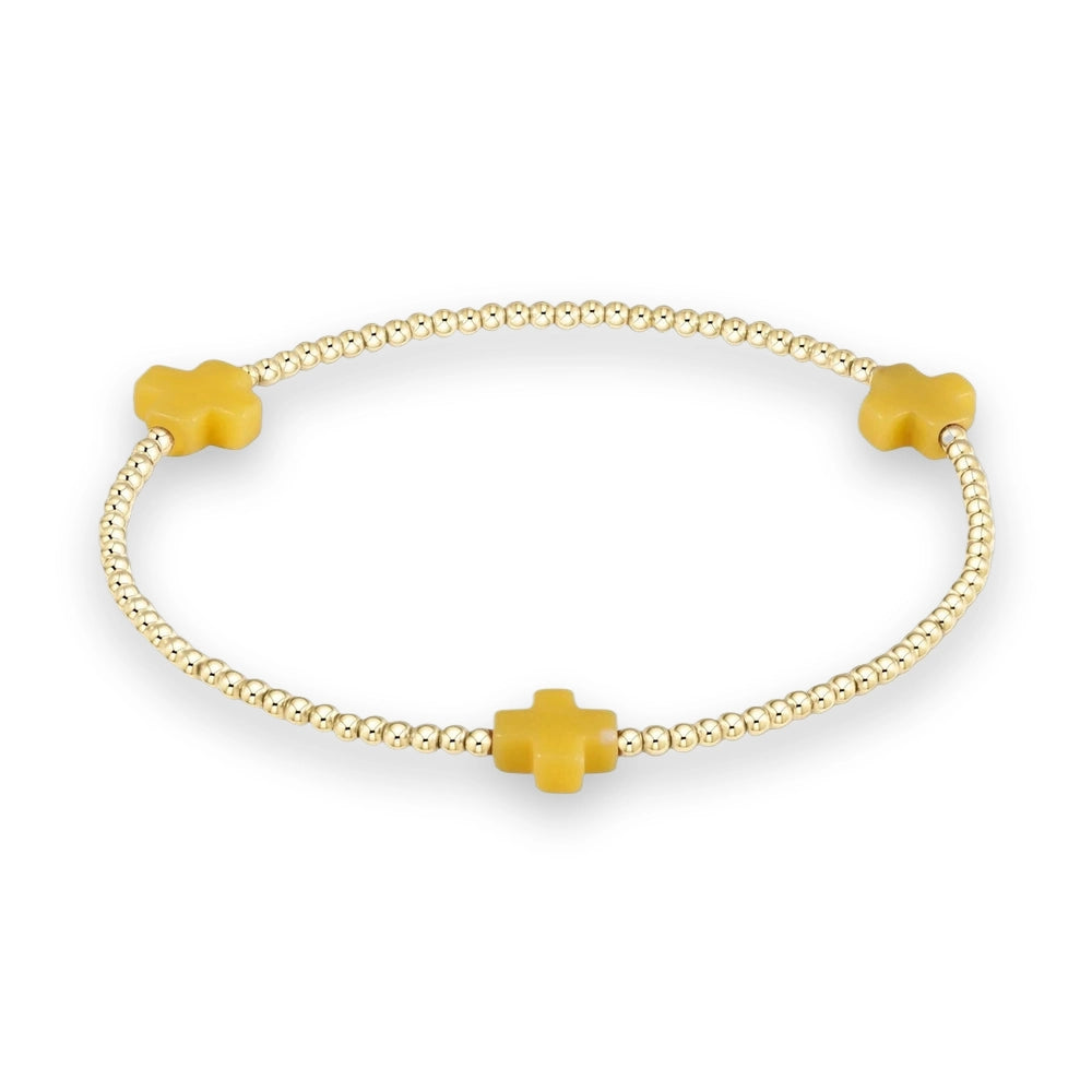 Gold beaded jewelry bracelet featuring three matte yellow crosses spaced symmetrically among polished spherical metallic beads on a neutral background