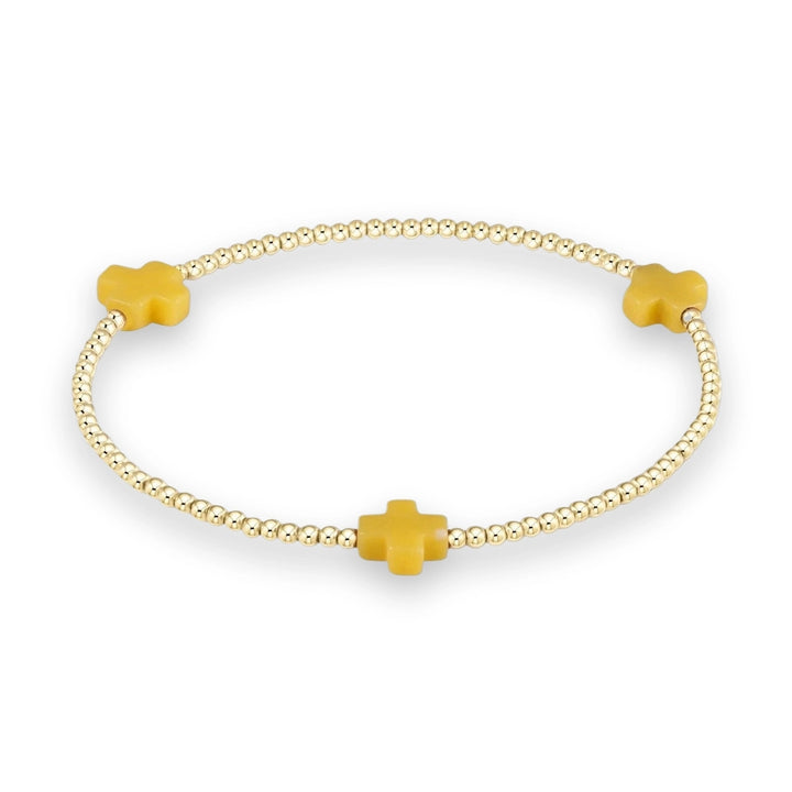 Gold beaded jewelry bracelet featuring three matte yellow crosses spaced symmetrically among polished spherical metallic beads on a neutral background