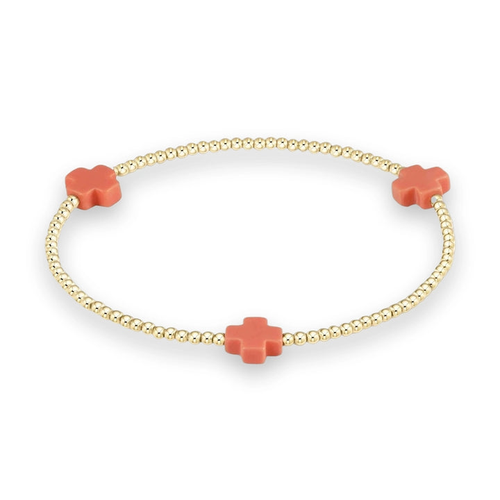 Gold-filled beaded bracelet by enewton design featuring three matte coral-colored cross charms and polished round beads on a neutral cream background