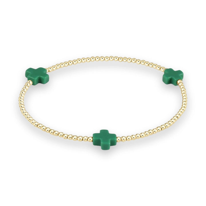 Gold beaded jewelry bracelet centered on a neutral background featuring three matte green cross charms and tiny polished spherical beads