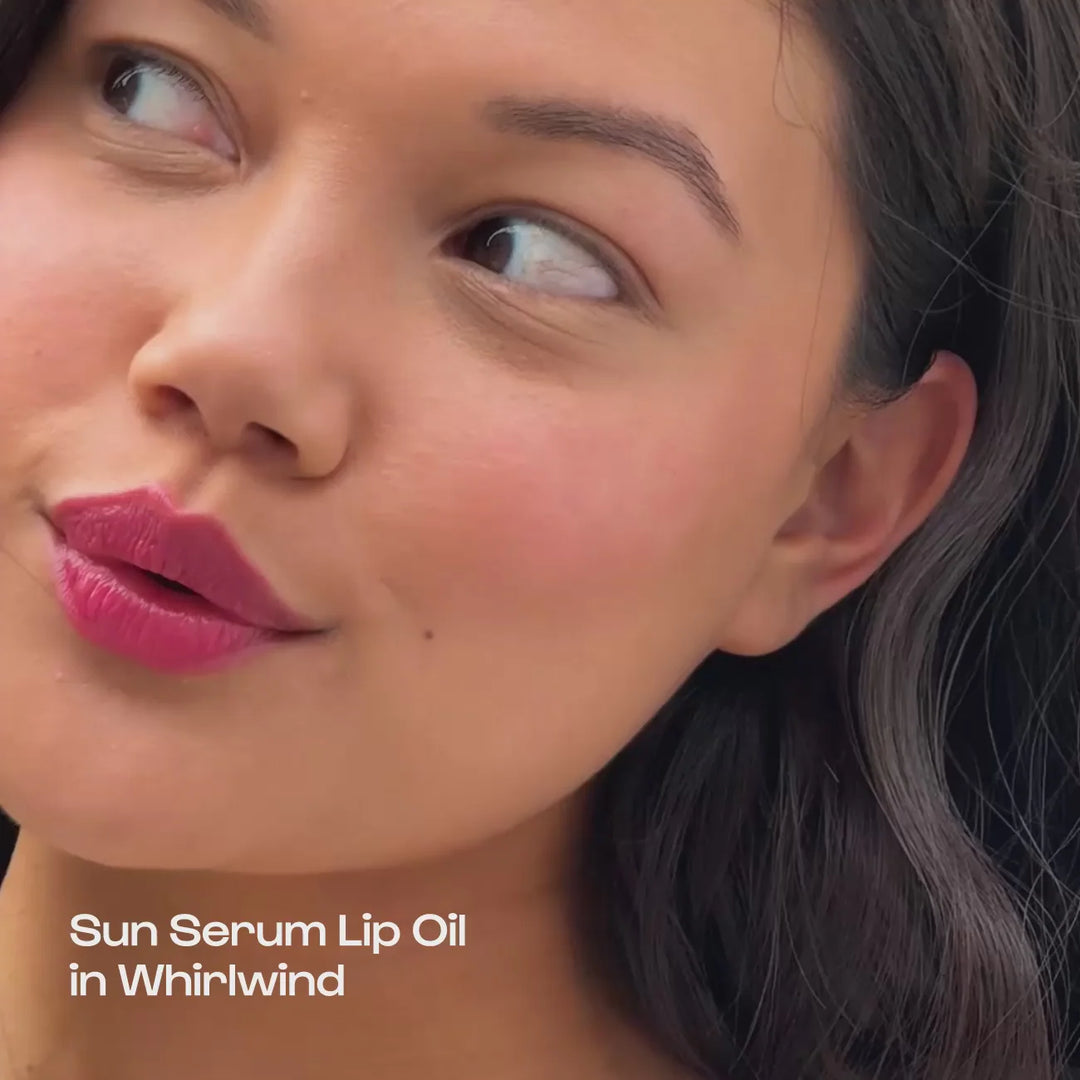 Close-up of a woman with pink lips puckered, with text "Sun Serum Lip Oil in Whirlwind"