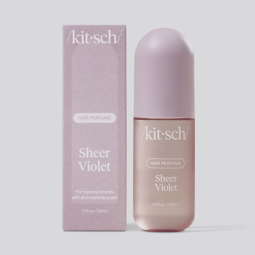 Studio product photograph by Kitsch featuring Sheer Violet hair perfume and its matching lavender box with the brand logo prominently displayed alongside a rounded matte cap and frosted glass bottle finish