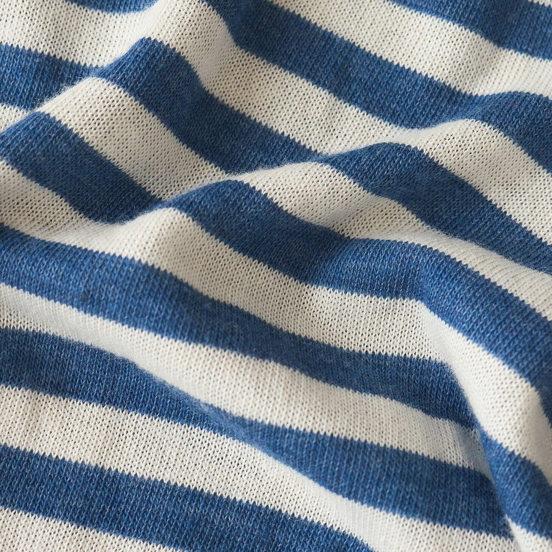 Knitted fabric textile macro detail of horizontal blue and white stripes featuring soft undulating folds, visible interlocking yarn loops, and a textured matte finish