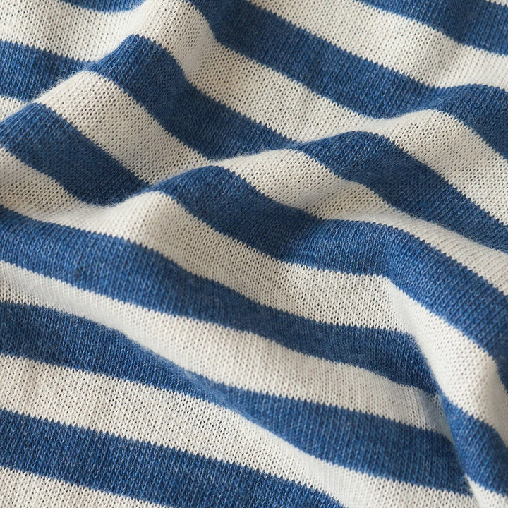 Knitted fabric textile macro detail of horizontal blue and white stripes featuring soft undulating folds, visible interlocking yarn loops, and a textured matte finish