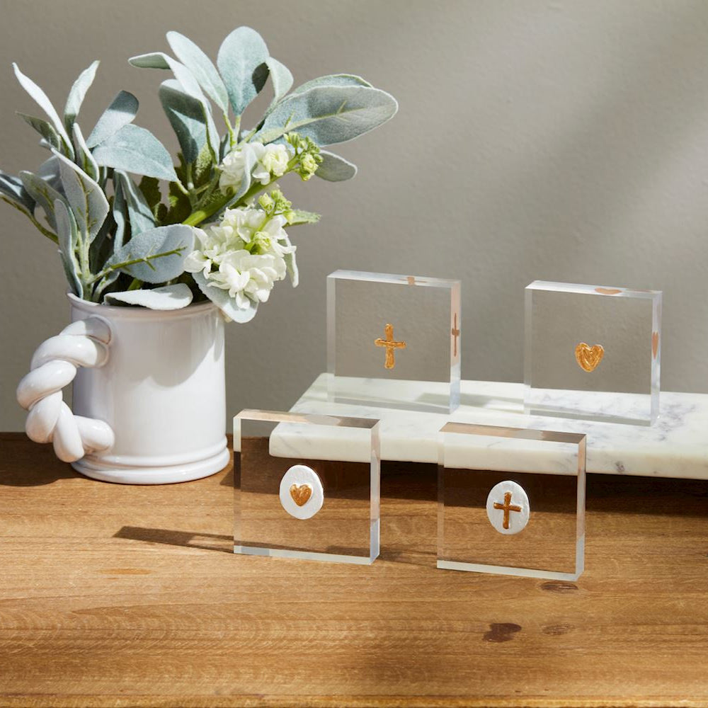 Acrylic art blocks by Deann Hebert featuring hand-painted gold metallic hearts and crosses displayed on a wooden surface beside a white ceramic mug with a braided handle and a white marble slab