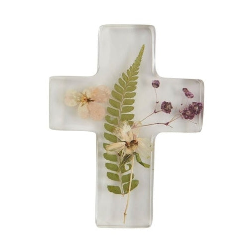 Resin cross sculpture containing preserved botanical specimens centered on a white background featuring a textured green fern frond, delicate purple floral sprigs, and a soft cream-colored blossom