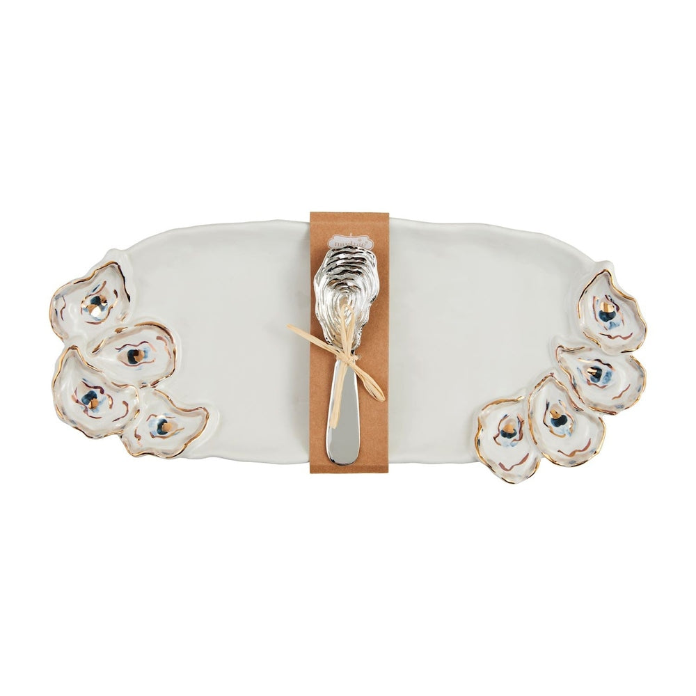 Ceramic stoneware platter by Mud Pie features a white oyster-themed serving tray with gold-rimmed hand-painted shell accents and a silver metal spreader with a textured shell handle secured by a kraft paper band and twine