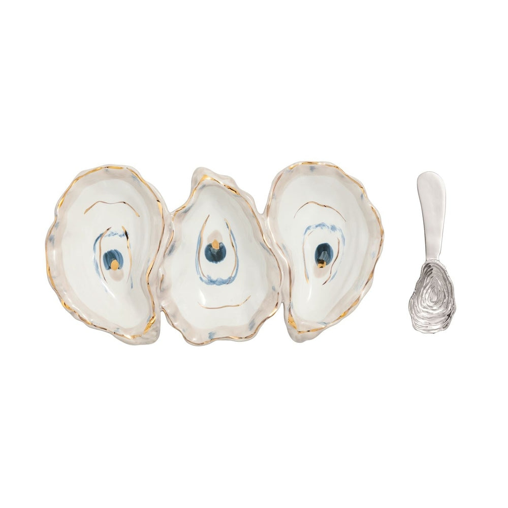 Stoneware serving dish by Aerin featuring three joined oyster shell compartments positioned on a white background with hand-painted gold-leaf rims, blue-hued interior accents, and a matching textured silver-tone oyster spoon