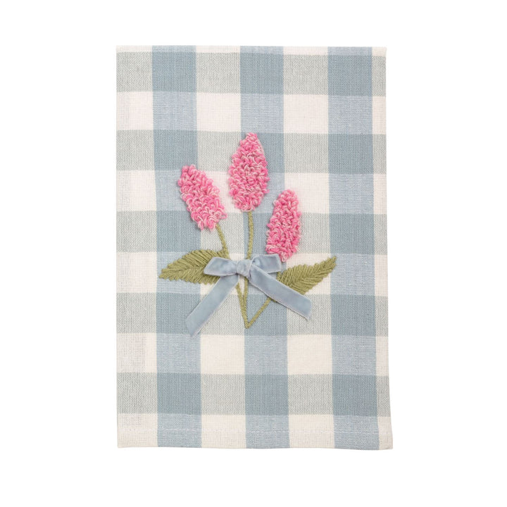 Embroidered linen tea towel featuring three textured pink floral sprigs centered on a light blue gingham background accented with a soft velvet ribbon bow and green stitched leaves