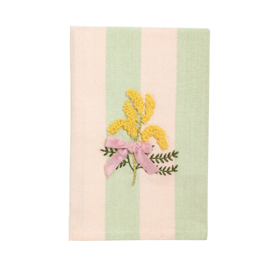 Embroidered linen notebook cover featuring a central bouquet of yellow textured mimosa blossoms tied with a pink velvet ribbon against a background of vertical pastel pink and mint green stripes