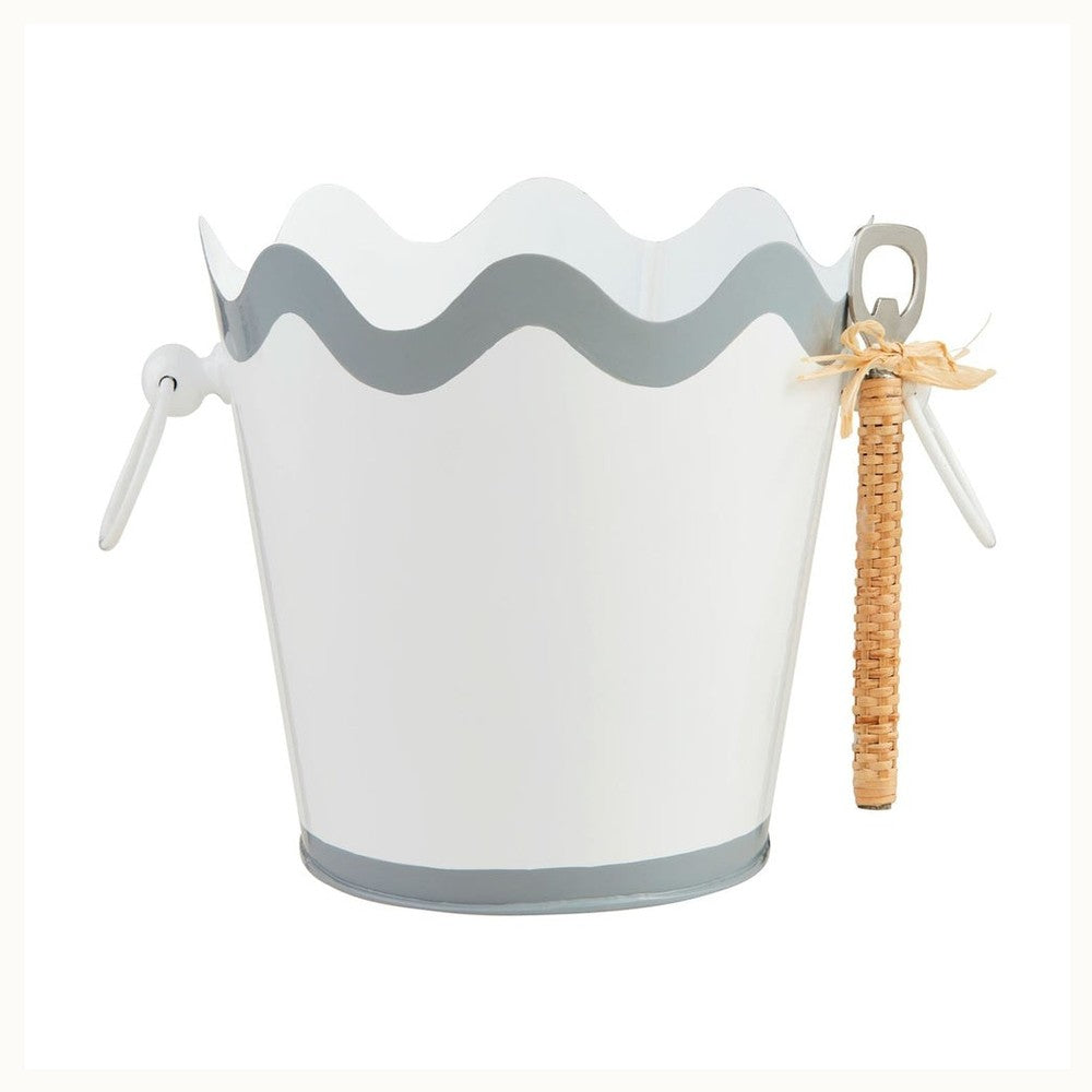 Enameled metal white ice bucket on a white background featuring a gray scalloped wavy border and a side-mounted bottle opener with a textured rattan handle and a natural raffia bow