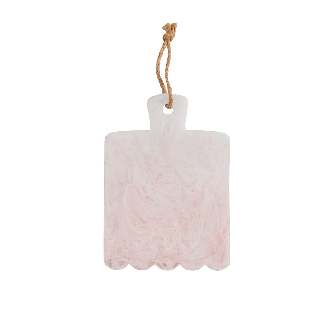 Hand-cast resin serving board featuring a pink and white marble swirl design with a unique scalloped bottom edge and a natural jute hanging loop isolated on a white background