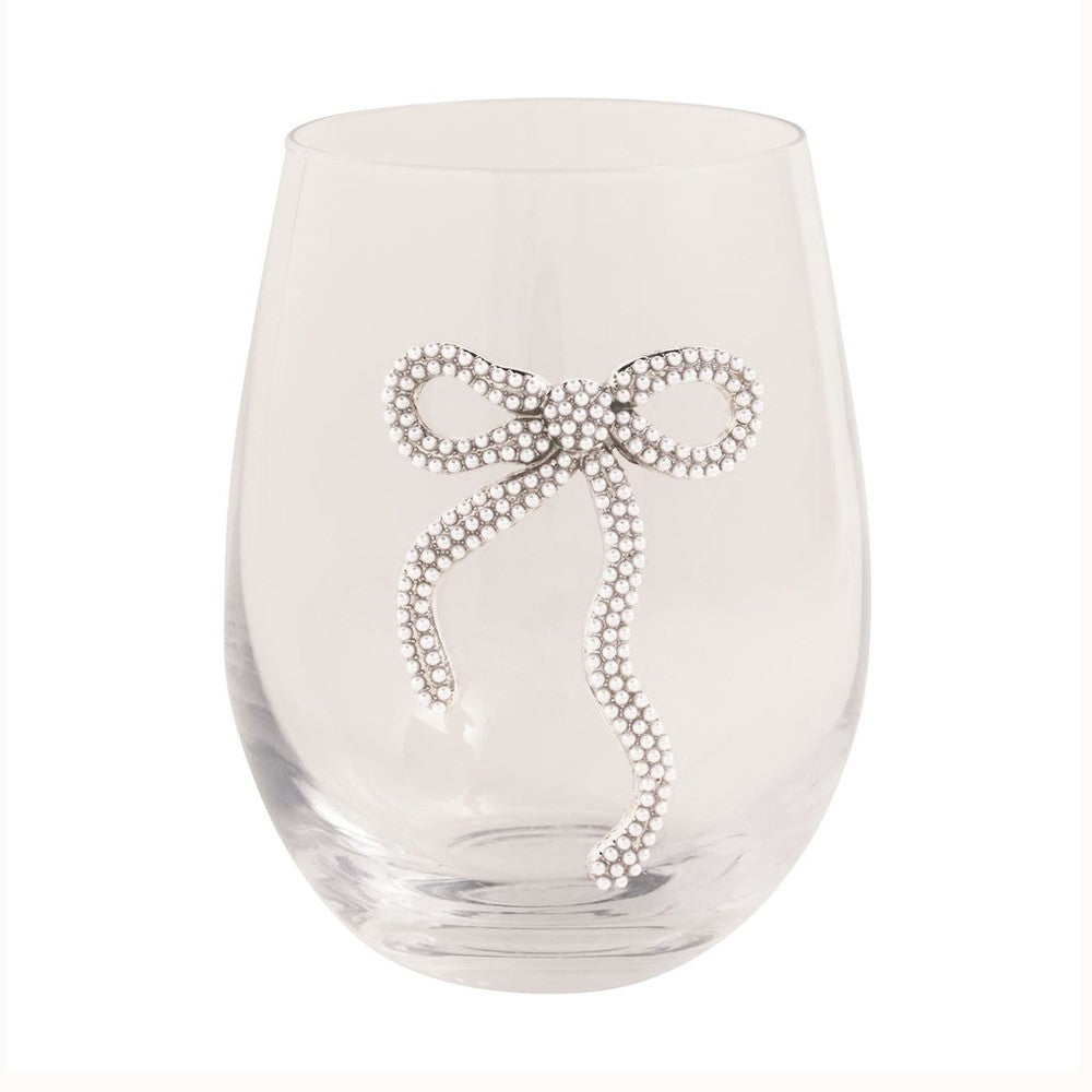 Handcrafted glass by Kim Seybert featuring a clear stemless wine glass set against a white studio background adorned with an intricate bow encrusted with shimmering white pearls and silver-toned metal with two elegant curving tails