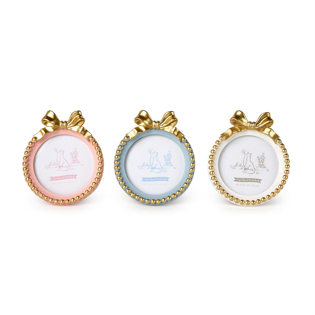 Resin decorative frames by Cupcakes &amp; Cartwheels featuring three small round photo frames in pastel pink, light blue, and cream white accented with ornate gold ribbon bows and beaded borders set against a plain white background